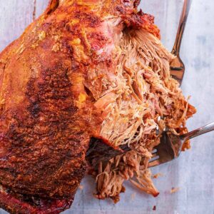 A leg of pulled lamb on a stone coloured surface.