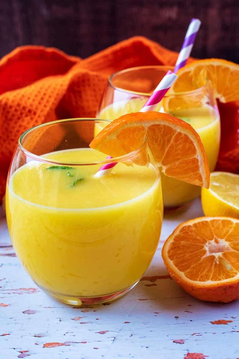 Immune Booster Juice in a glass with an orange slice and striped straw.