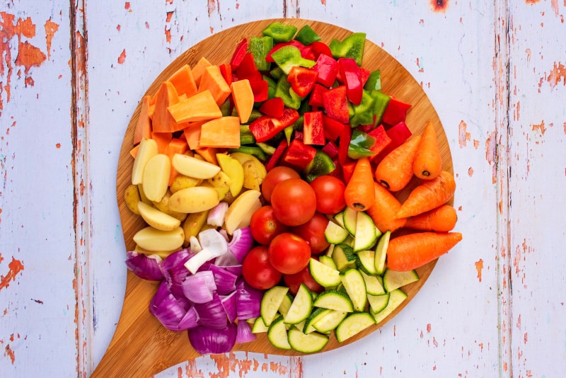 A circular chopping board with chopped vegetables on it.