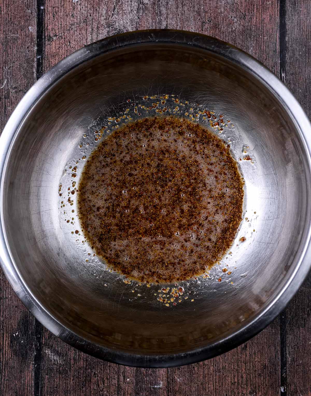 A large mixing bowl containing a mixture of oil, mustard and honey.