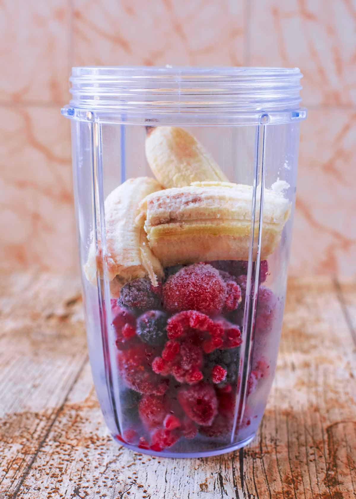 Frozen berries and banana in a blender jug.