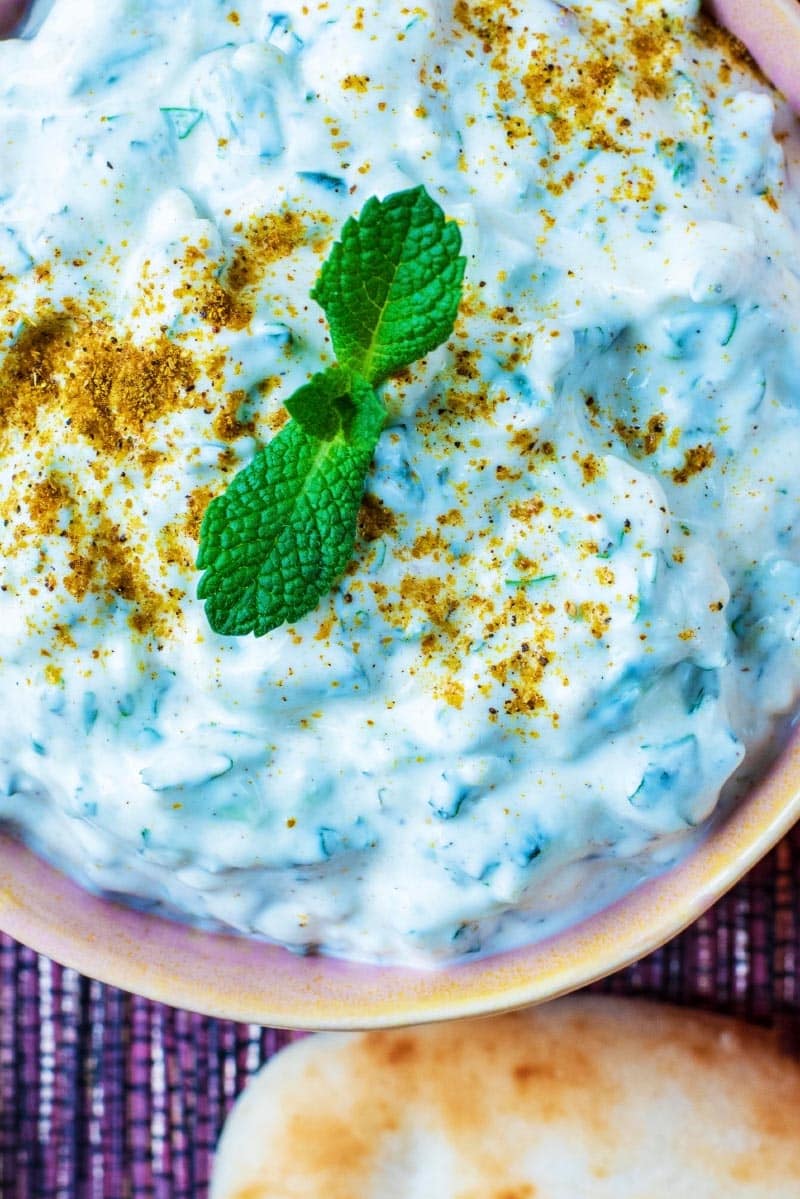 Raita topped with mint leaves and a sprinkling of garam masala.