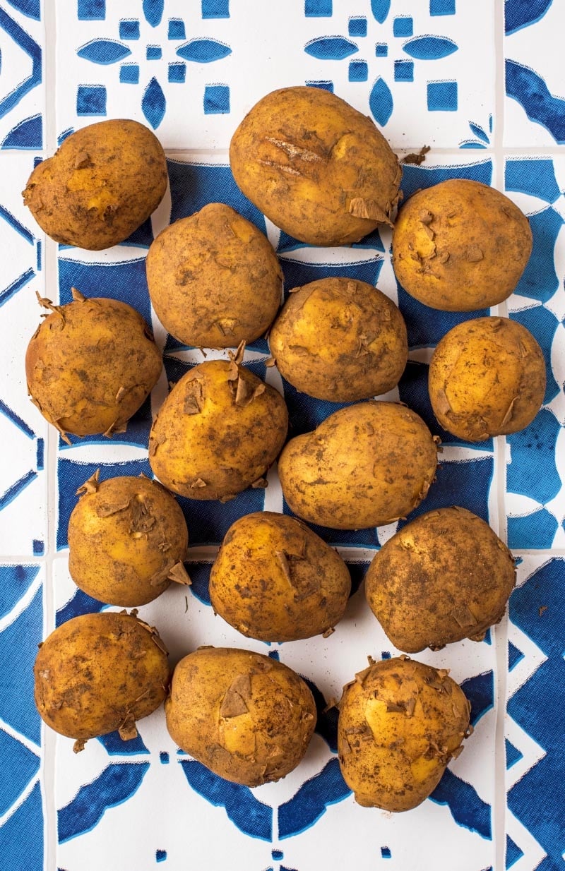 Dirty potatoes on a blue and white tiled surface