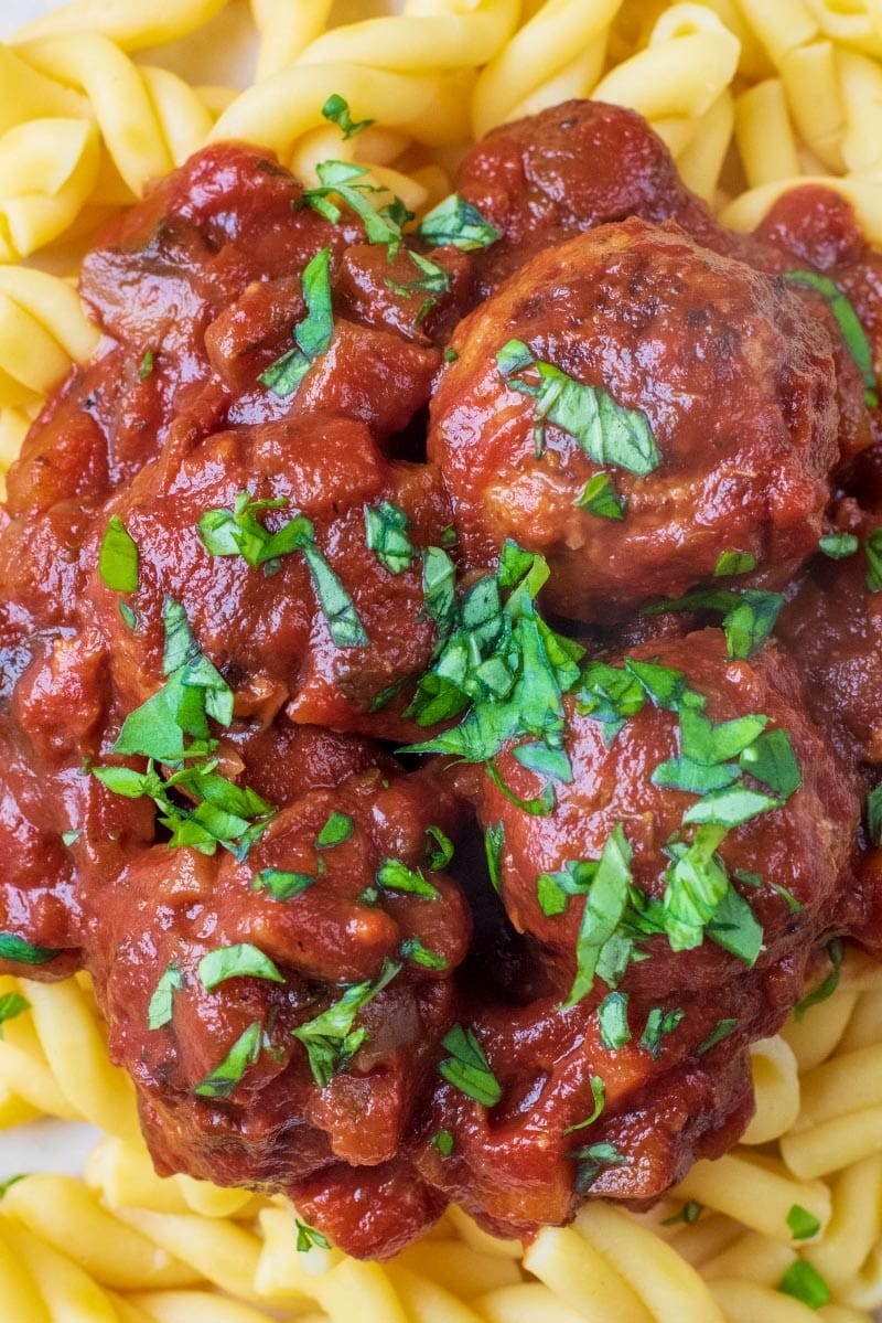 Slow cooked meatballs on pasta with a sprinkling of chopped basil on top