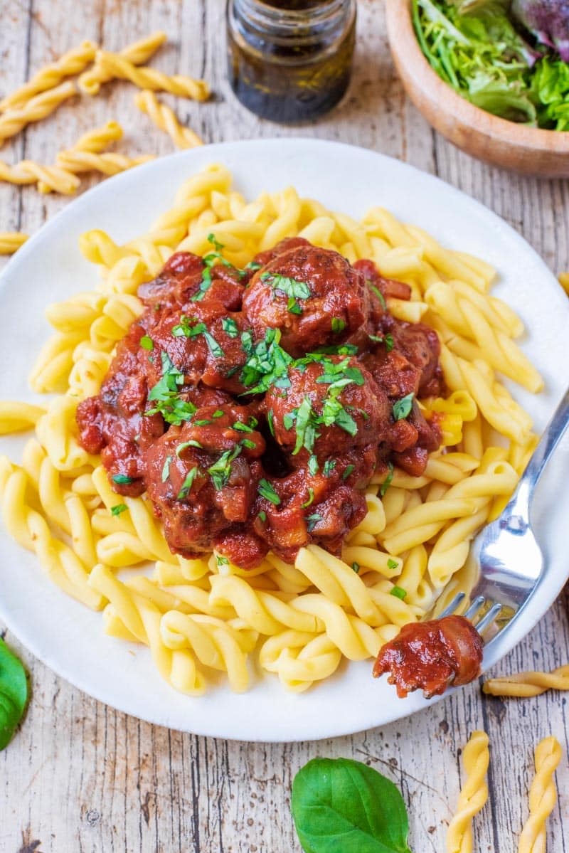 Meatballs in a sauce on top of pasta shapes.