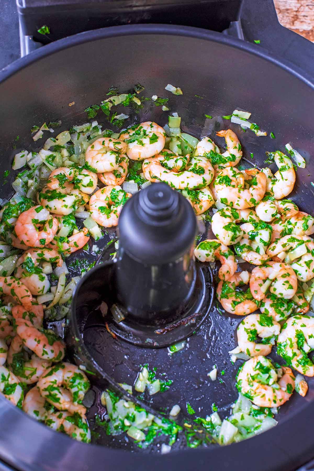 Cooked prawns and herbs in an air-fryer with its lid open.