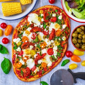 Easy naan pizza next to a pizza slice and some corn on the cob.