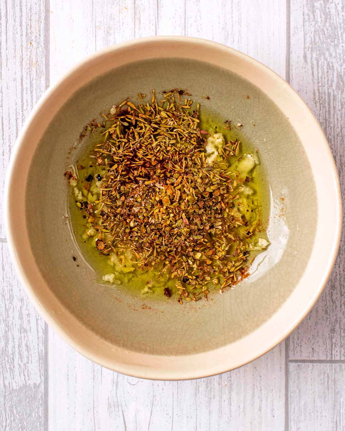 A herb and oil dressing in a small bowl.