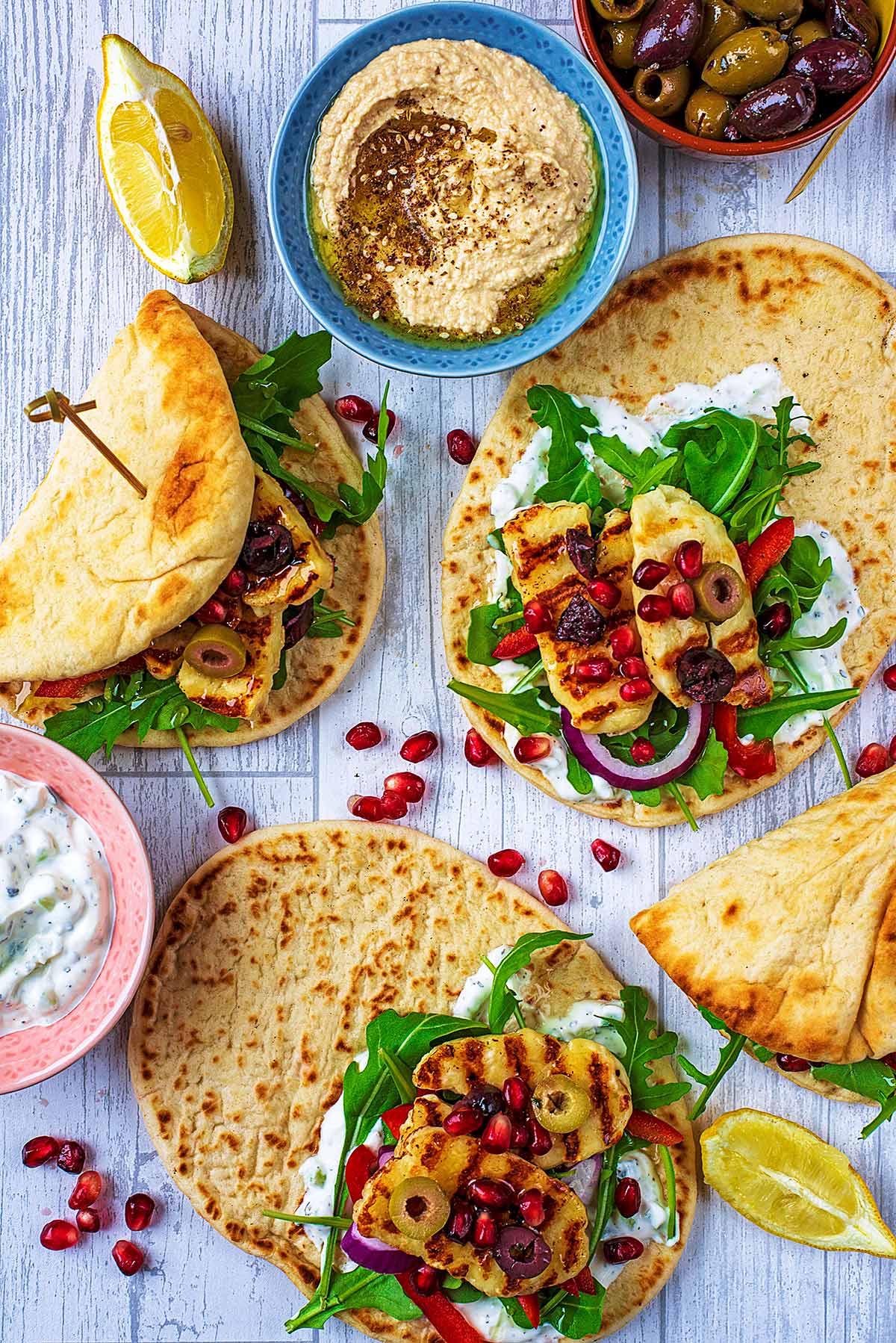 Halloumi Flatbreads next to bowls of hummus and tzatziki.