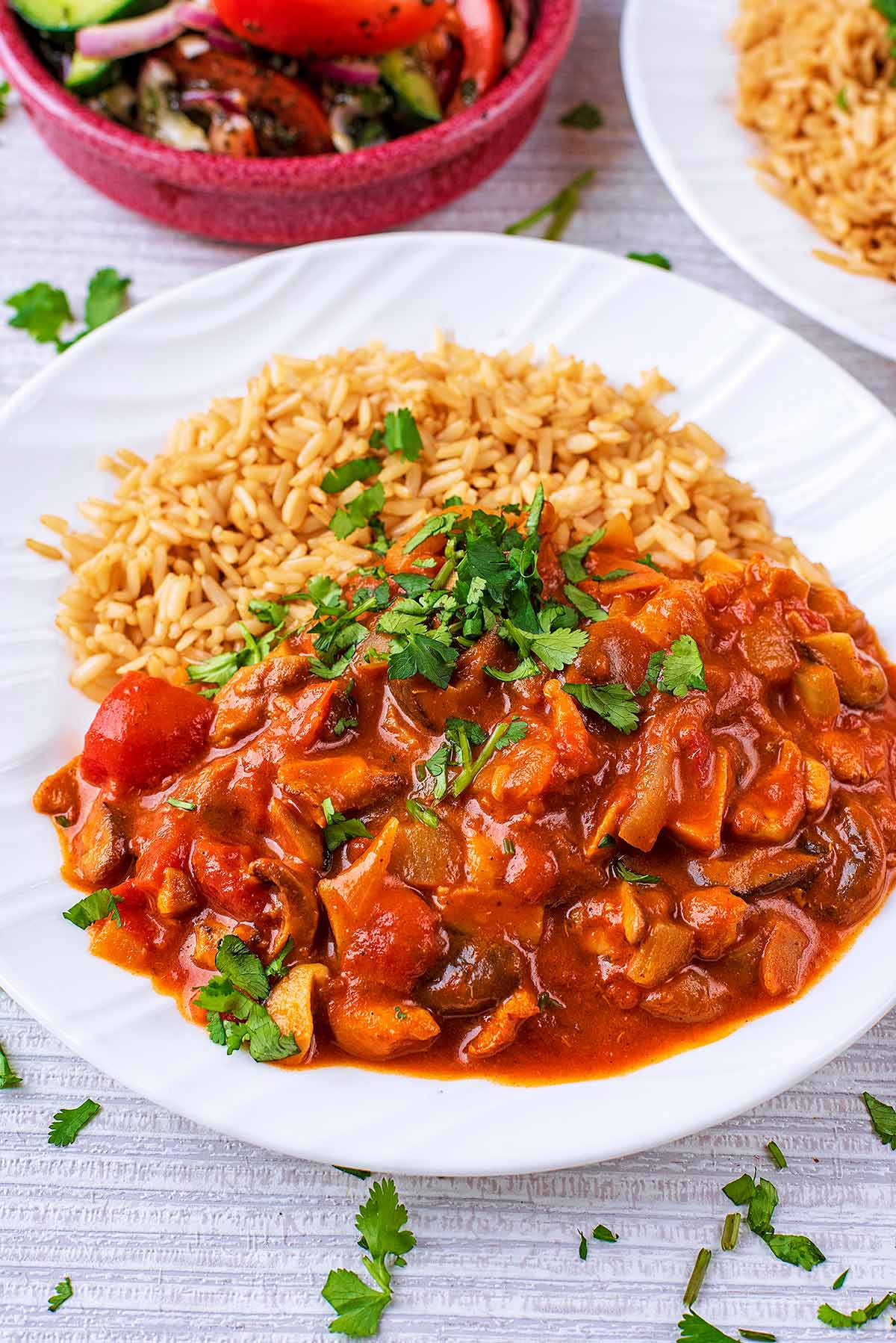 Mushroom Curry on a white plate topped with chopped coriander.