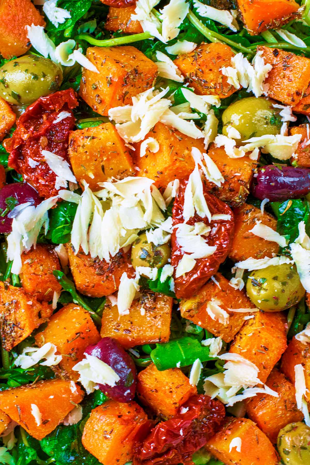 Roasted butternut squash, sundried tomatoes and shavings of cheese on a salad.