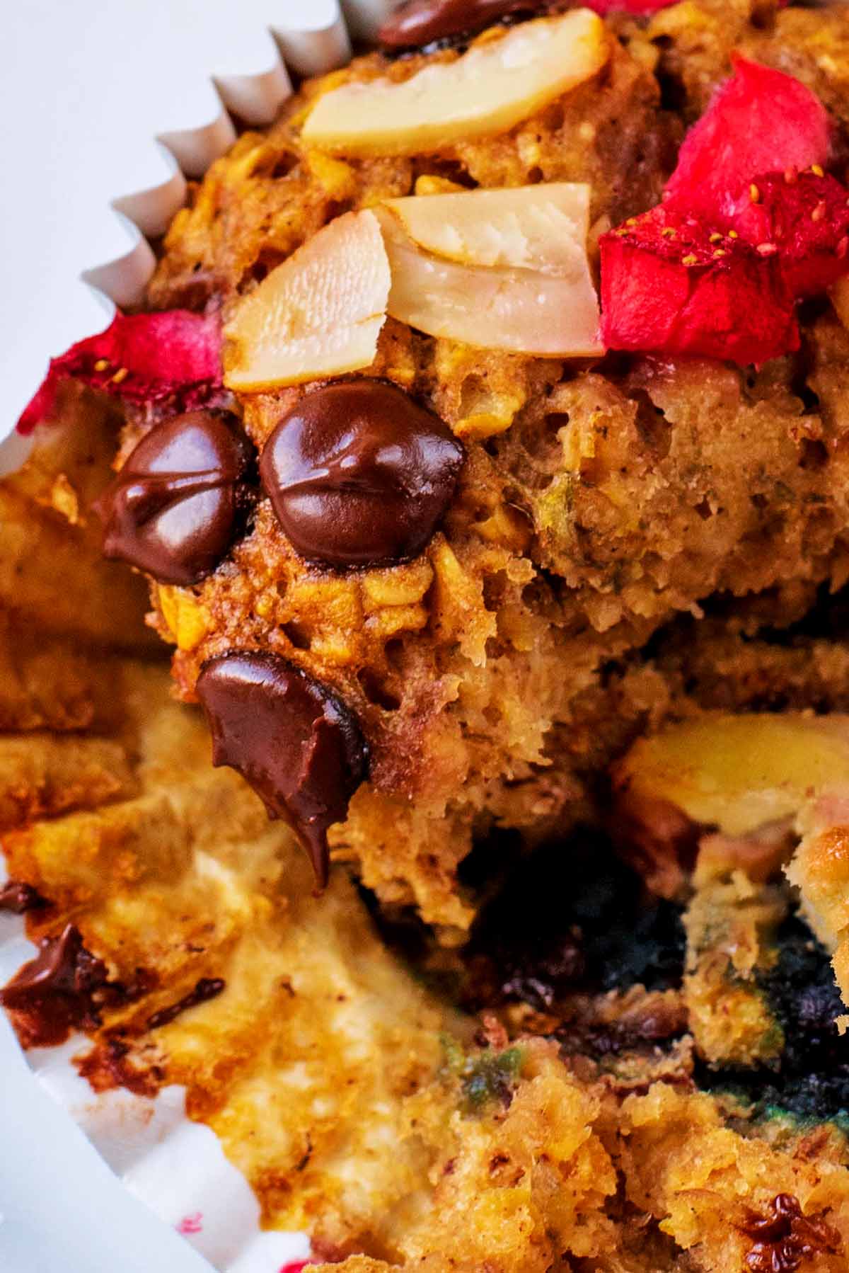 A broken open muffin showing berries and chocolate chips on the inside.