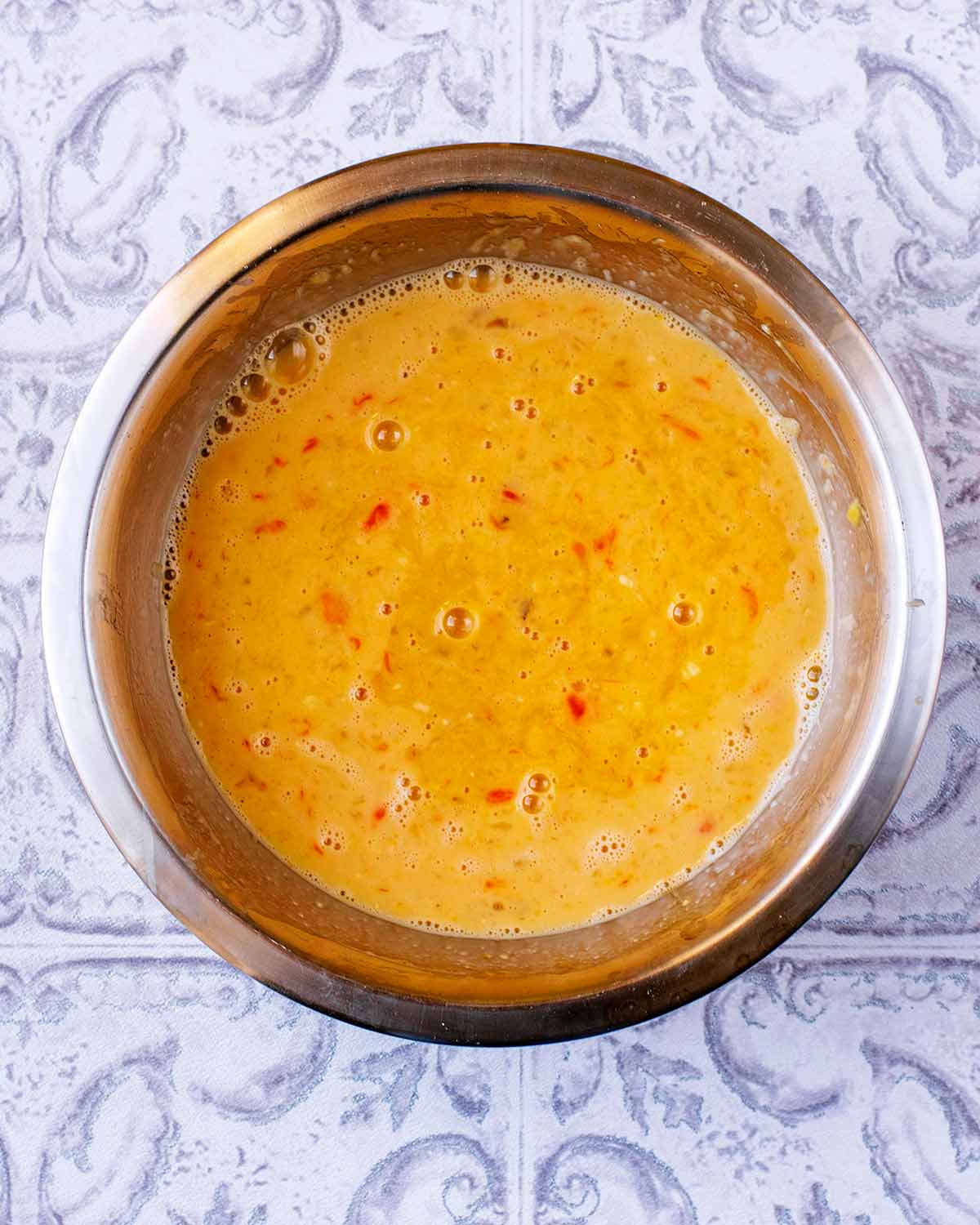 A mixing bowl with whisked eggs in it.