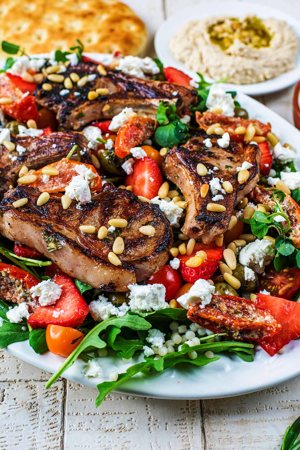 a large plate of salad topped with lamb chops.