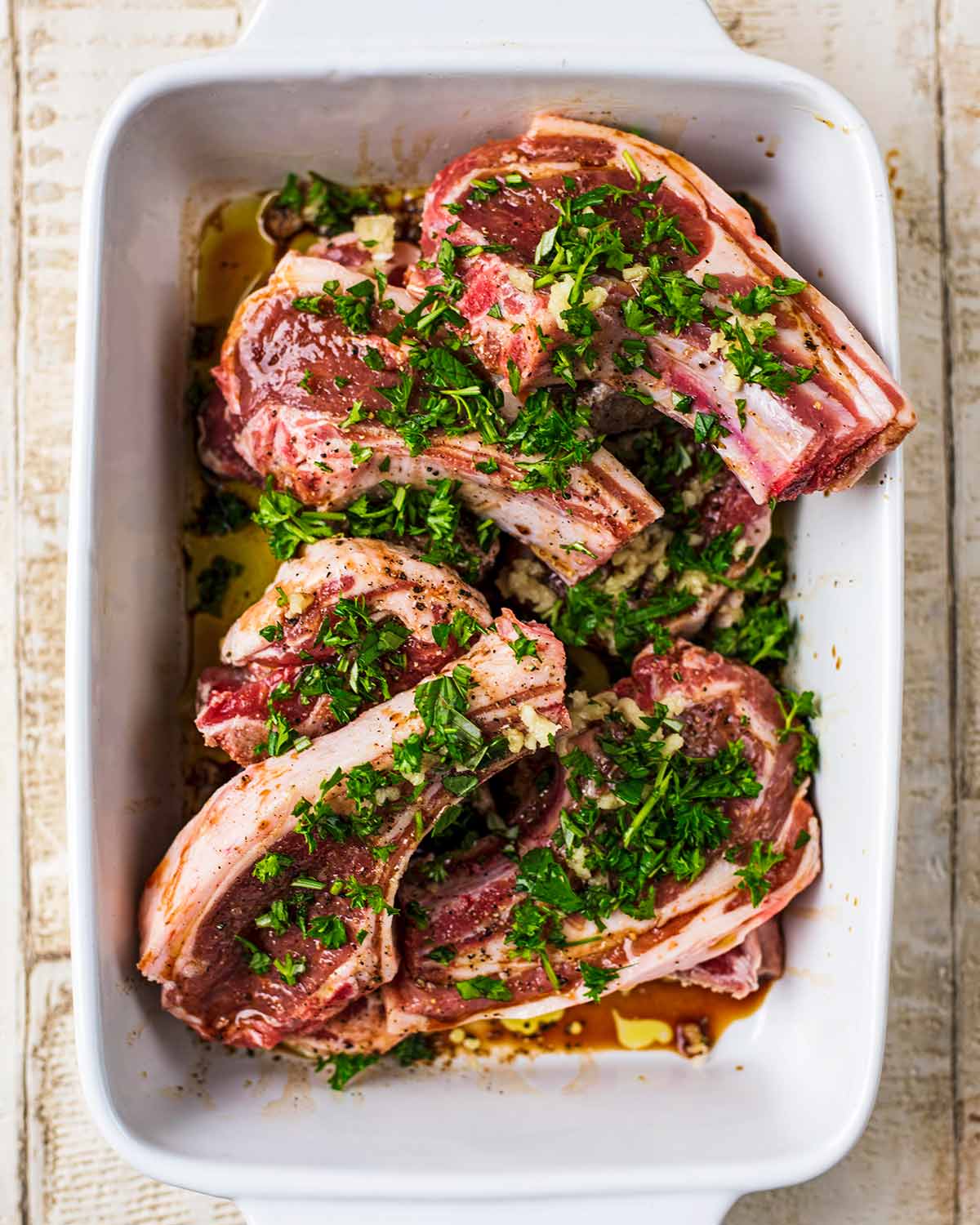 A baking dish containing marinating lamb chops.