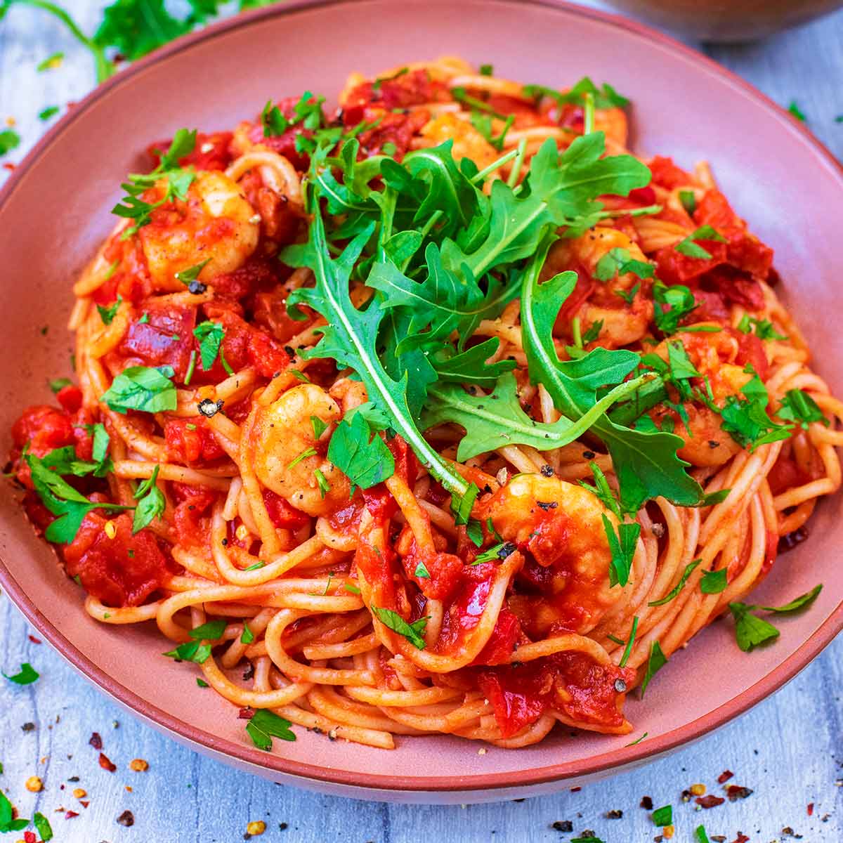 Prawn and Chorizo Pasta in a bowl with rocket lettuce leaves on top.