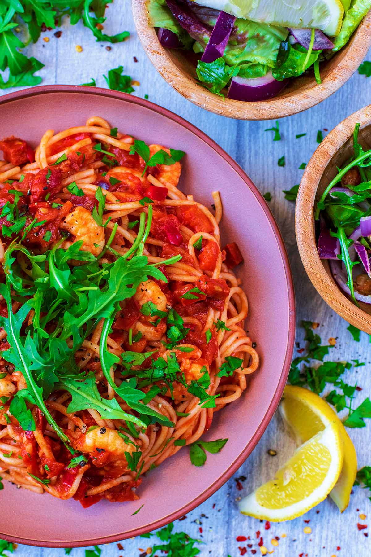 Prawn and Chorizo Pasta in a large pink bowl, topped with salad leaves.