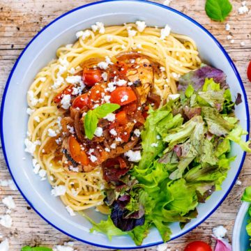 Slow Cooker Balsamic Chicken on a bed of spaghetti next to some salad leaves.