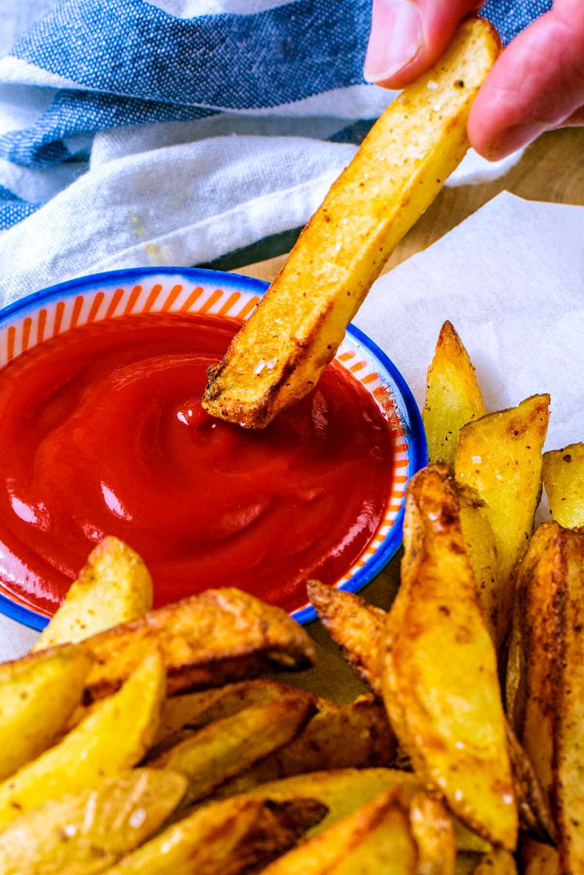 An air fried chip being dipped into some ketchup.