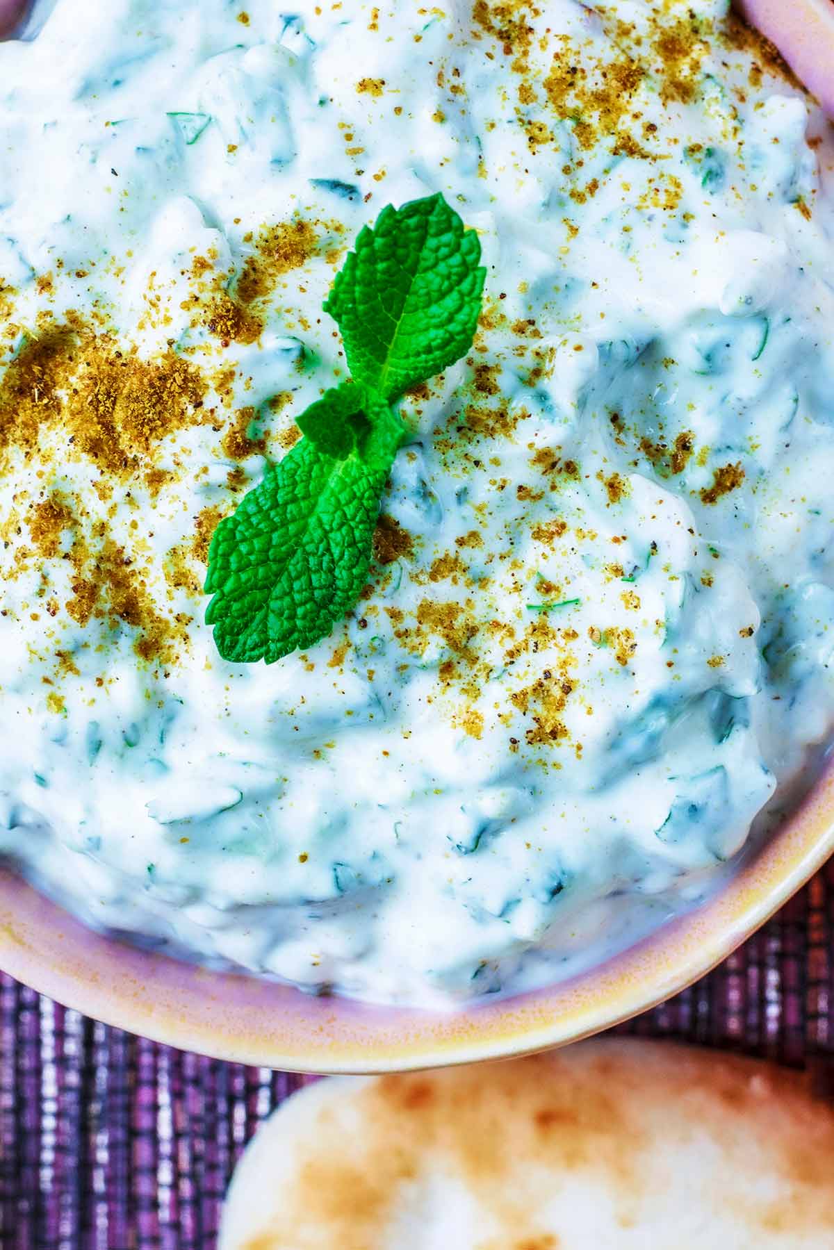 Raita topped with mint leaves and a sprinkling of garam masala.