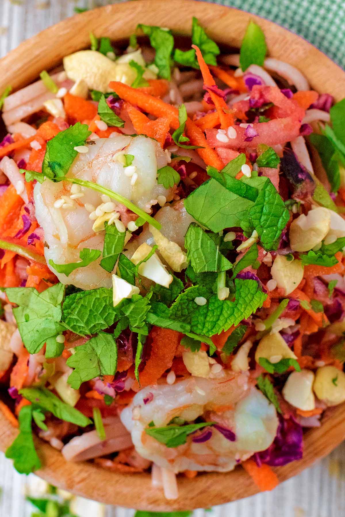A bowl of cooked prawns mixed with noodles and stir fry vegetables.
