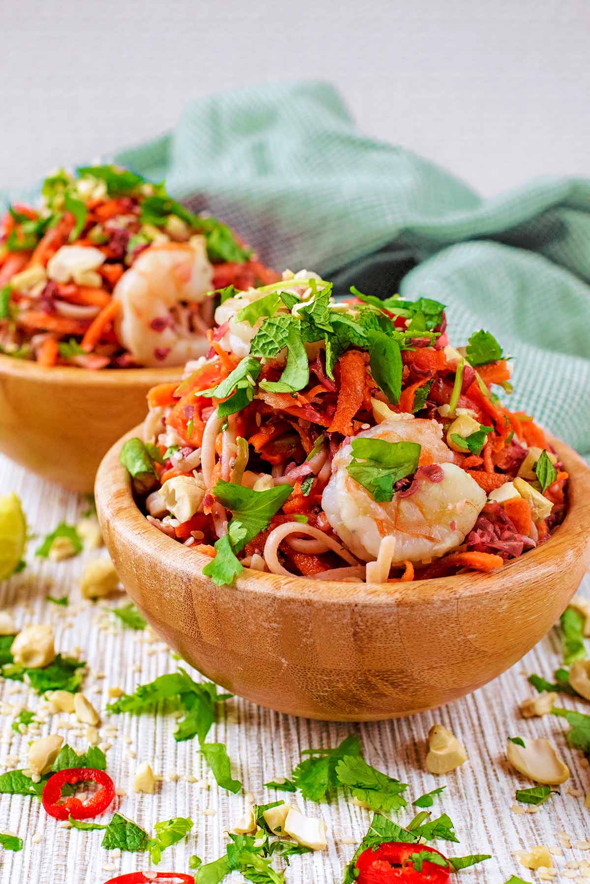 A wooden bowl of noodles topped with cooked king prawns.