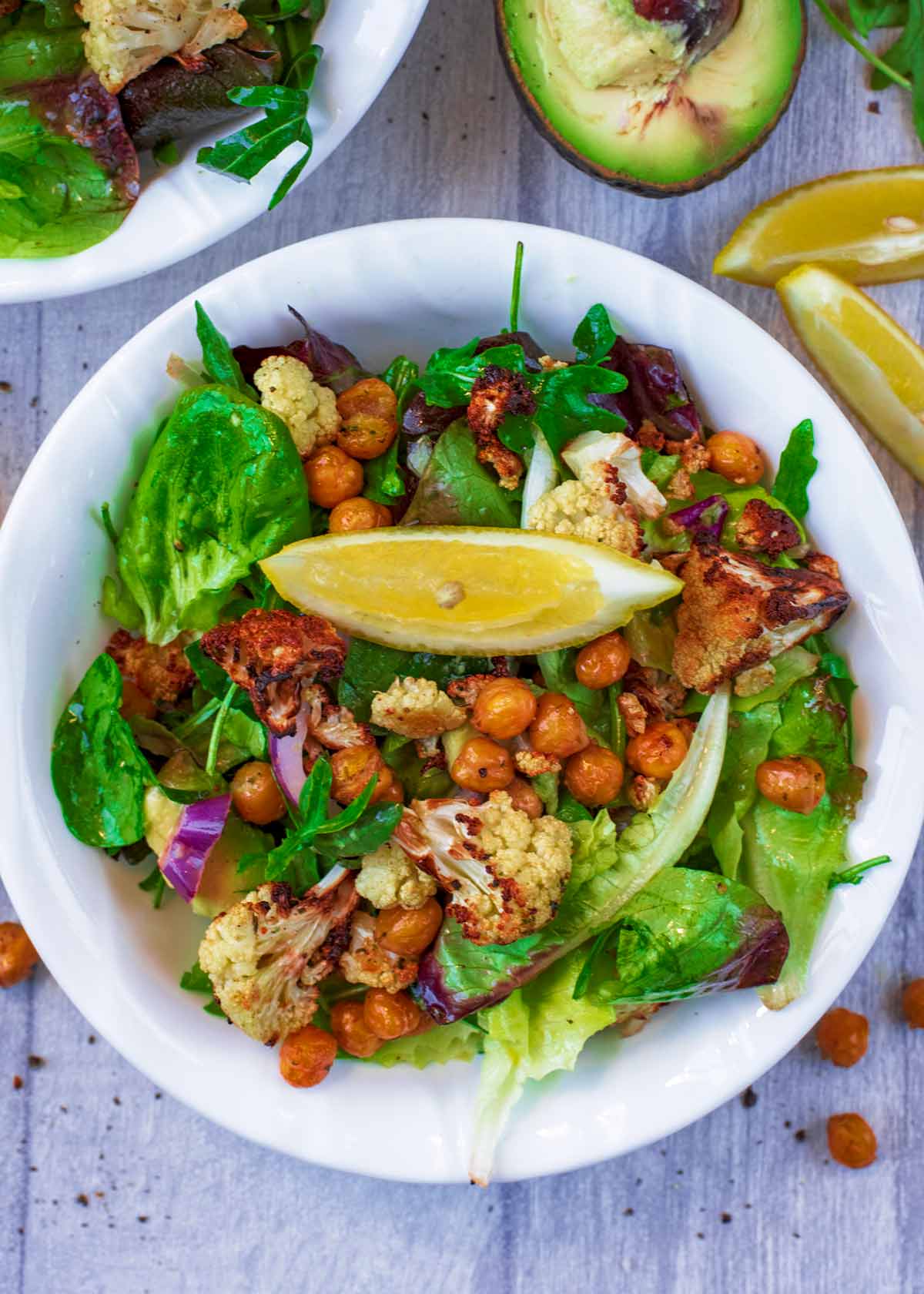 A bowl of salad topped with cauliflower and chickpeas.