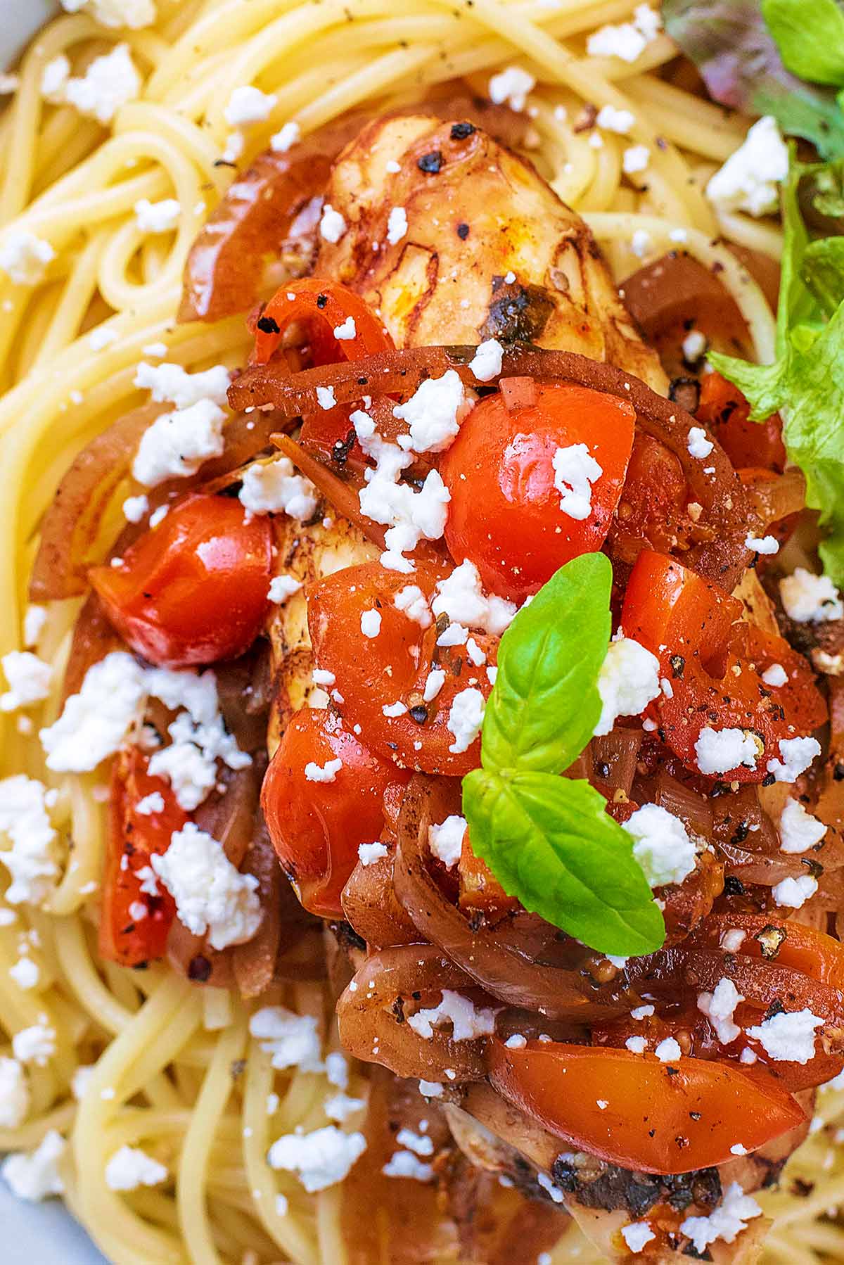 Cooked tomatoes and basil leaves on top of chopped cooked chicken.