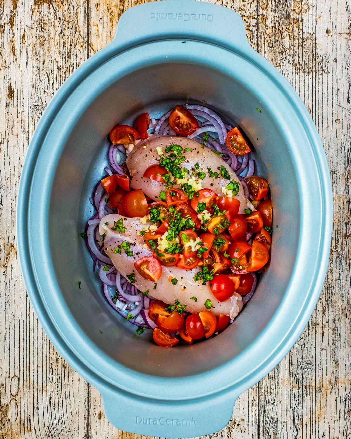 Chopped tomatoes, crushed garlic and chopped herbs added to the slow cooker.