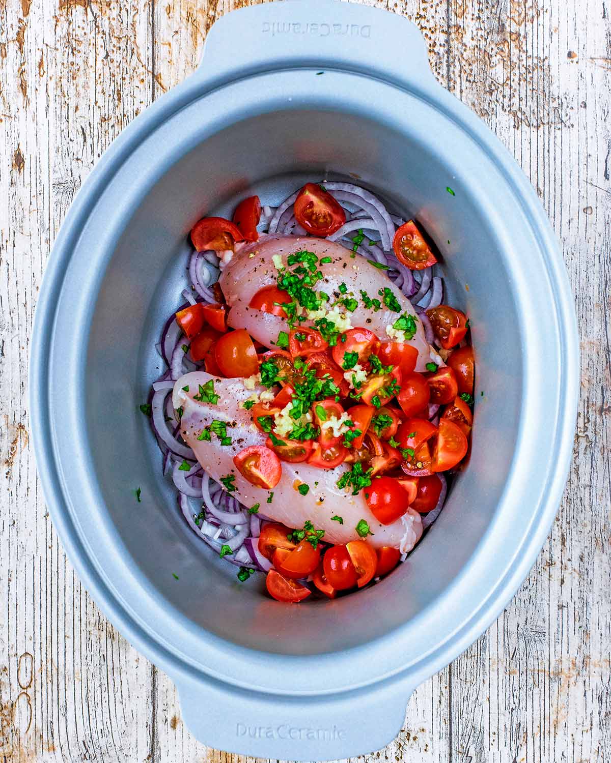 Chopped tomatoes, crushed garlic and chopped herbs added to the slow cooker.