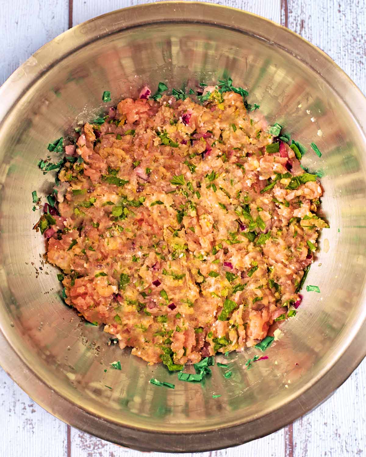 Lamb mince, spices and herbs mixed together in a bowl.