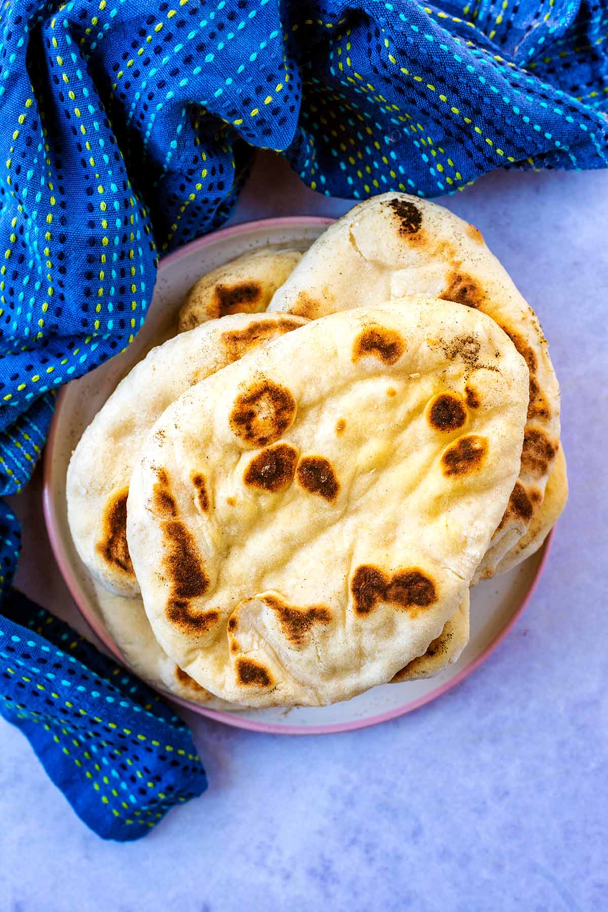 A stack of naan breads next to a blue towel.