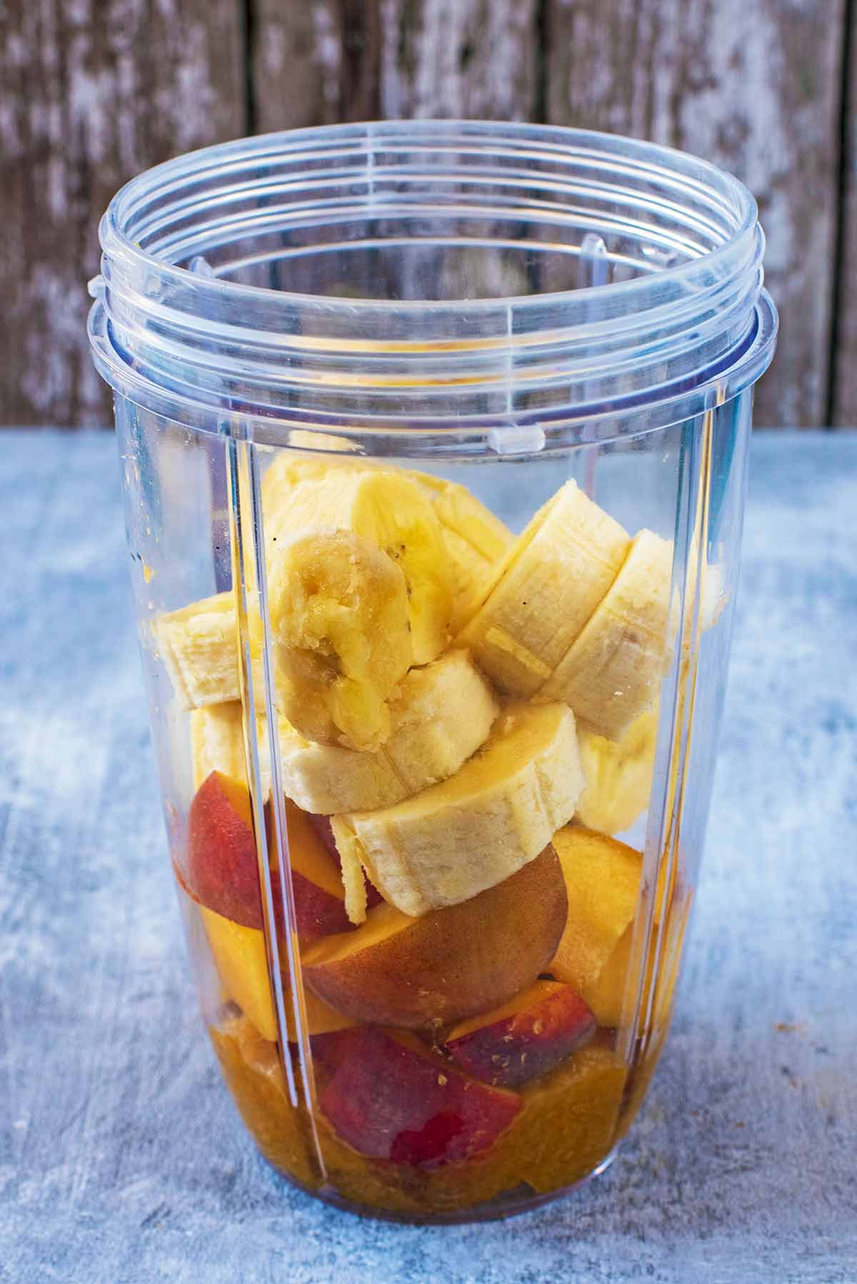 Chopped banan and chopped peach in a blender jug.