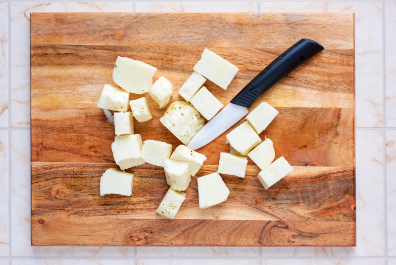 Halloumi cut into cubes on a wooden chopping board.