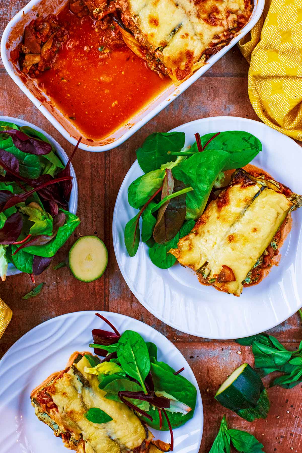 Two plates of lasagna with salad.