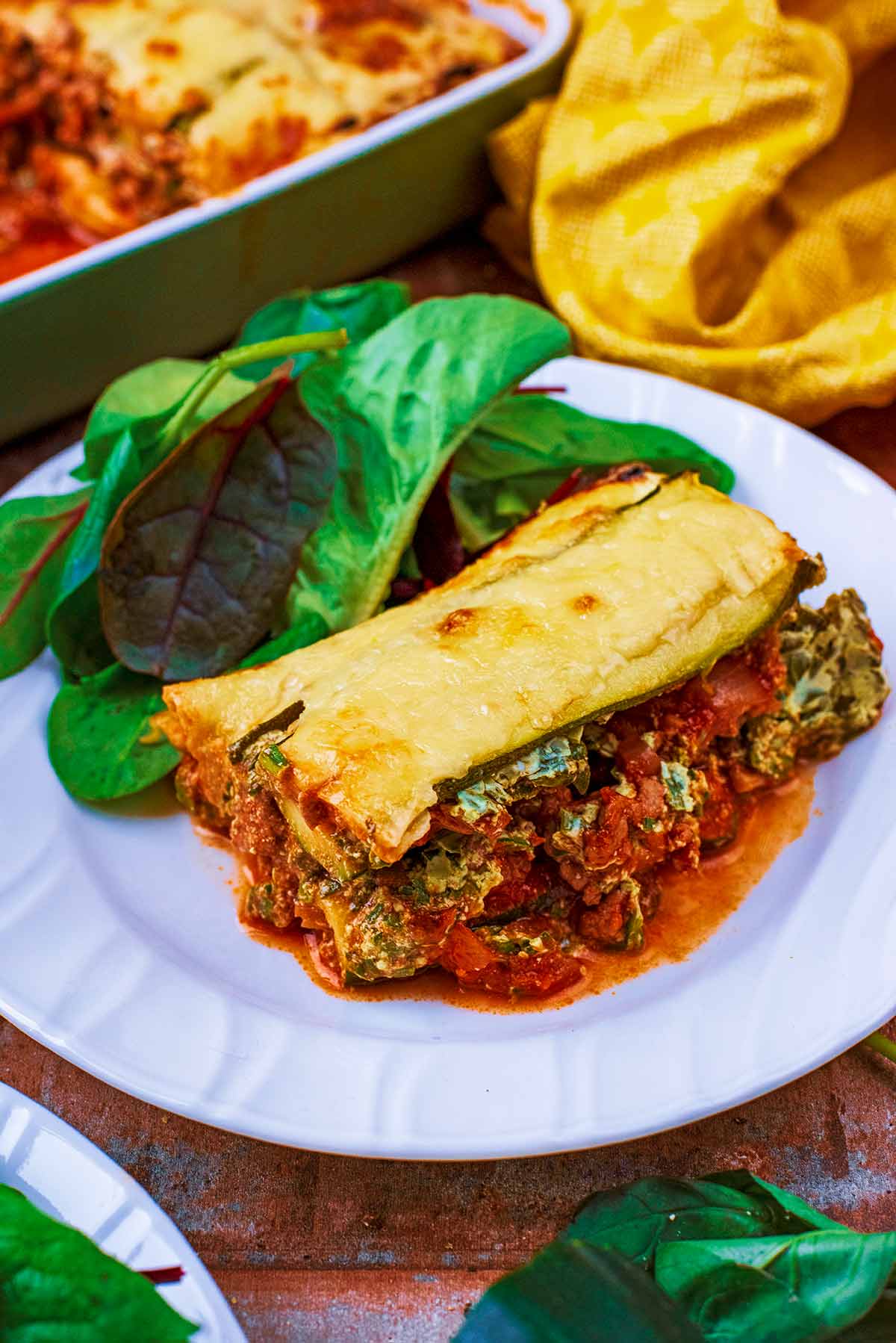 A white plate with lasagna and salad.
