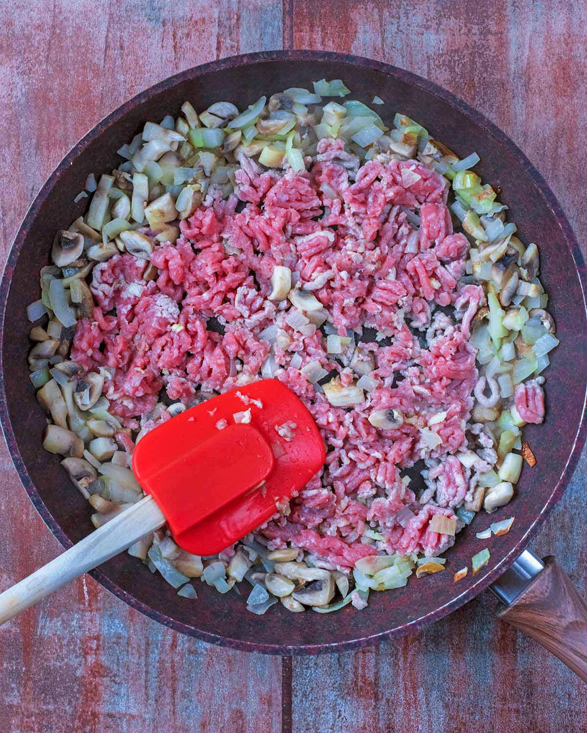 Chopped onion, mushrooms, ground turkey and garlic in a frying pan.