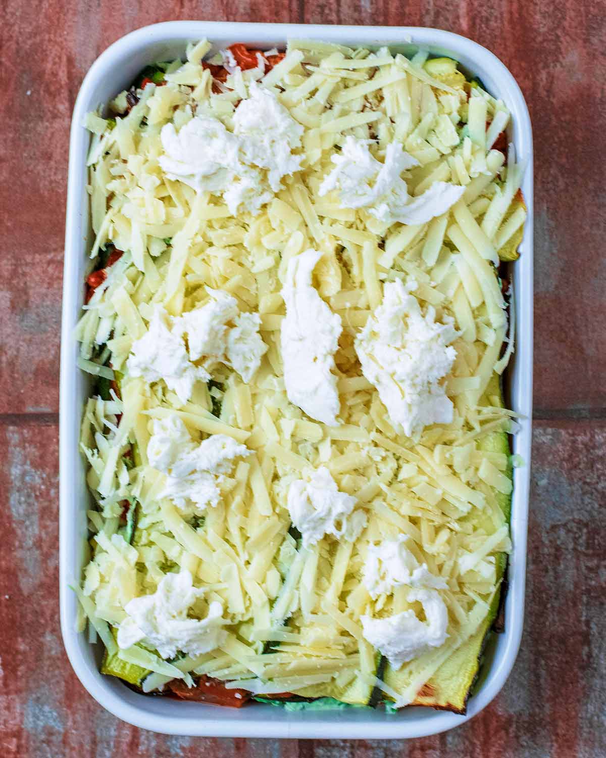 Grated cheddar and torn mozzarella added to the top of the lasagna.