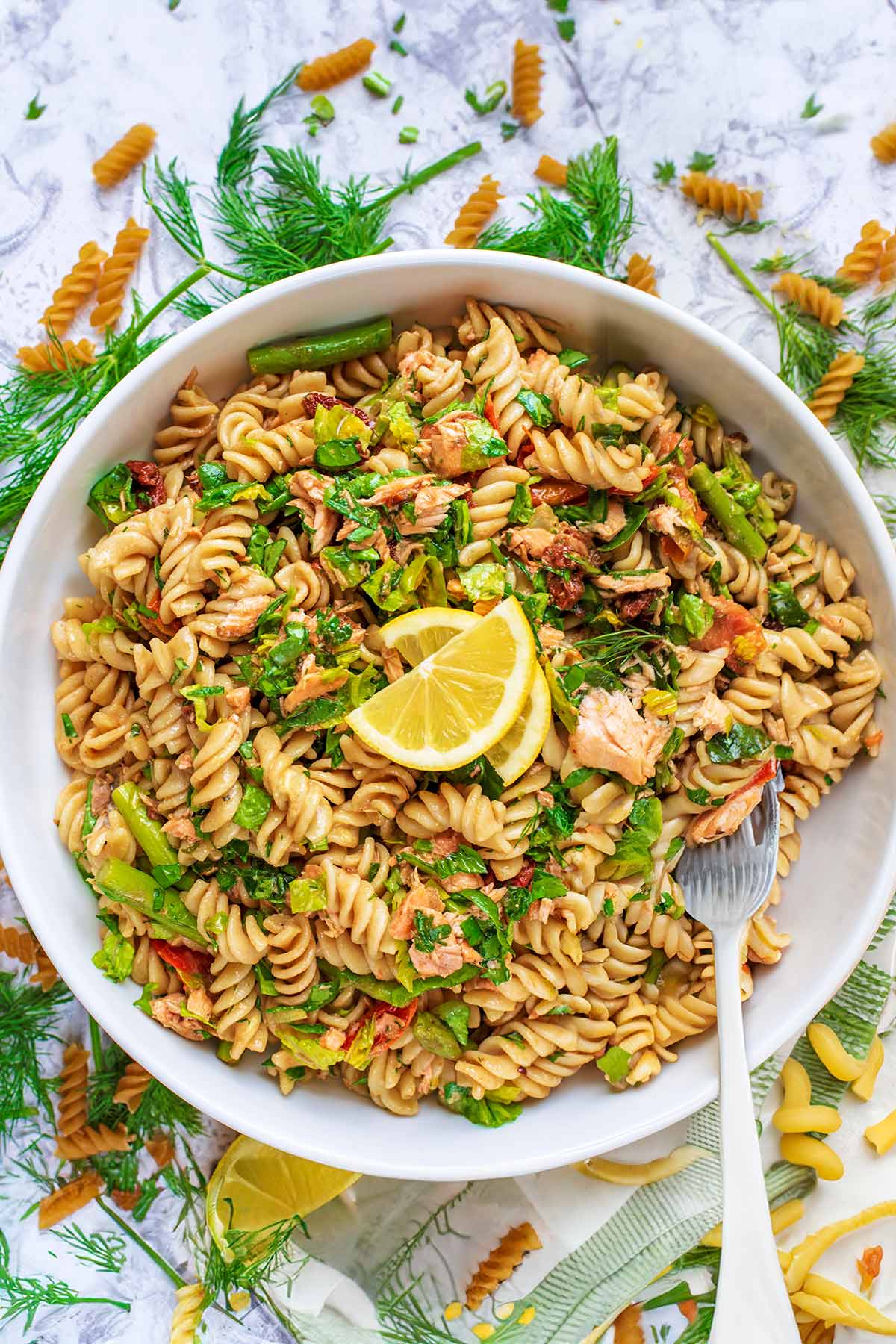 A large white bowl full of pasta salad, with a fork in it.