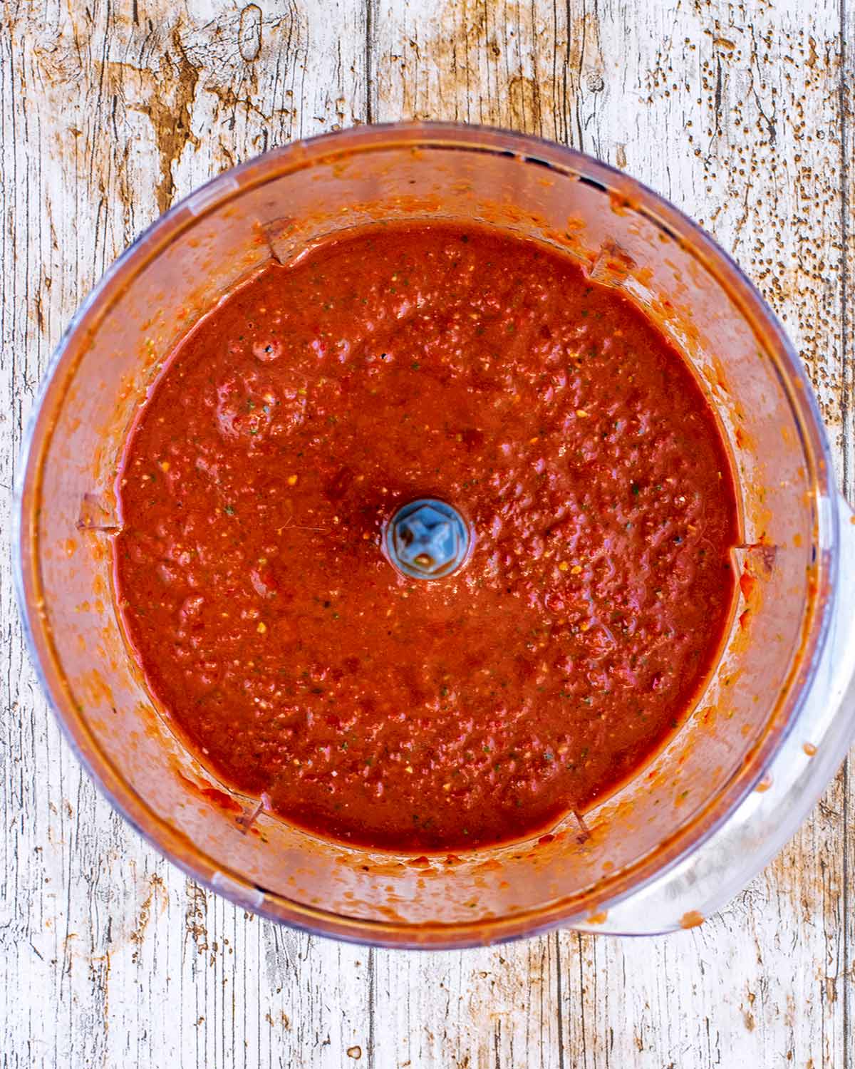 A food processor containing blended tomato sauce.