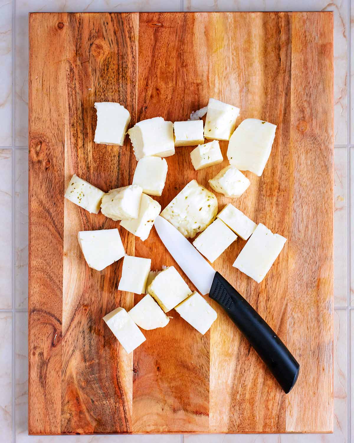 Halloumi cut into cubes on a wooden chopping board.
