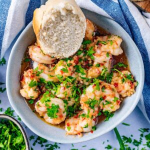 Gambas pil pil in a bowl with a chunk of bread.