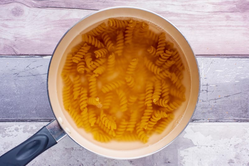 A saucepan containing cooked fusilli pasta in water.