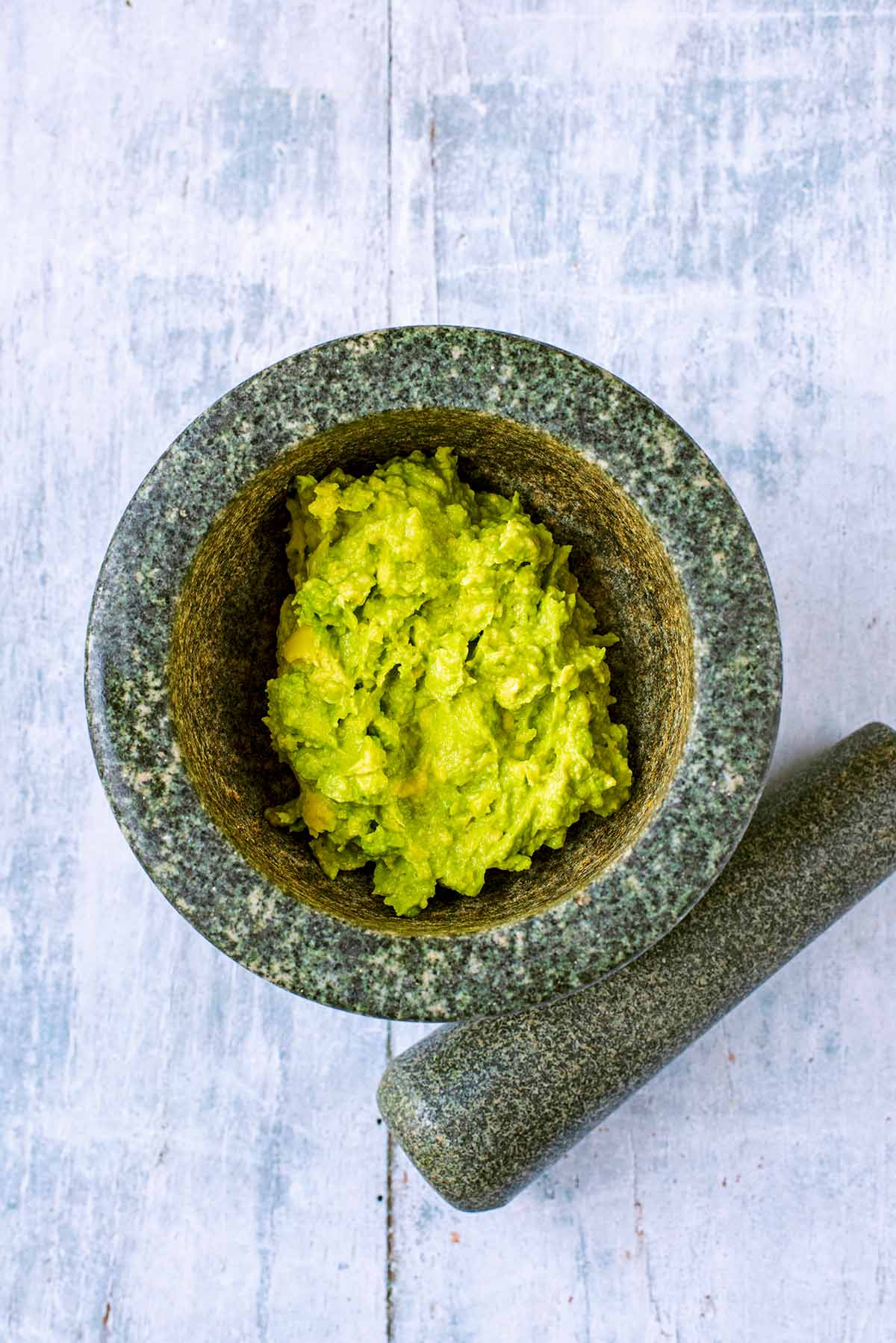 A pestle and morter full of mashed avocado.