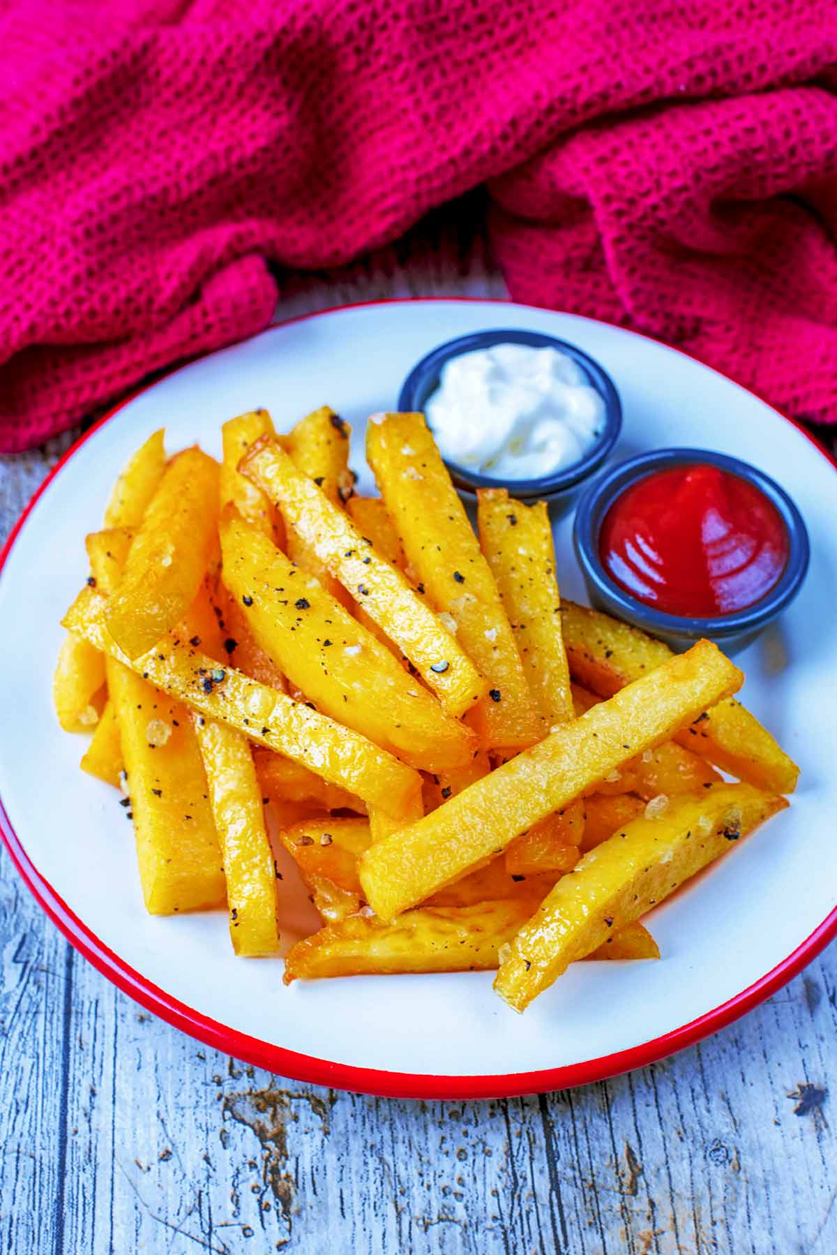 Polenta chips on a red rimmed plate with two pots of dip.