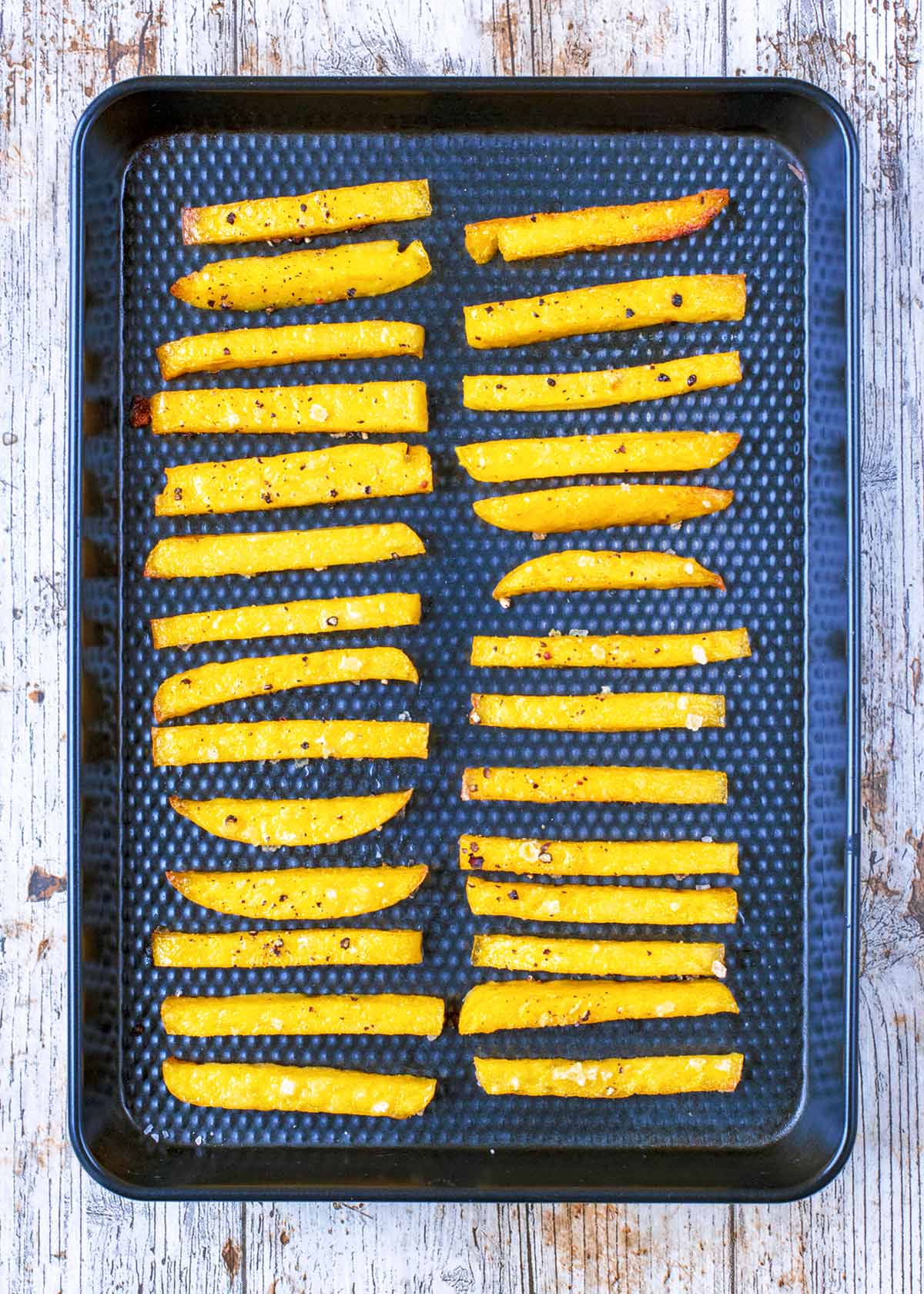 Oven Baked Polenta Fries on a black baking tray.