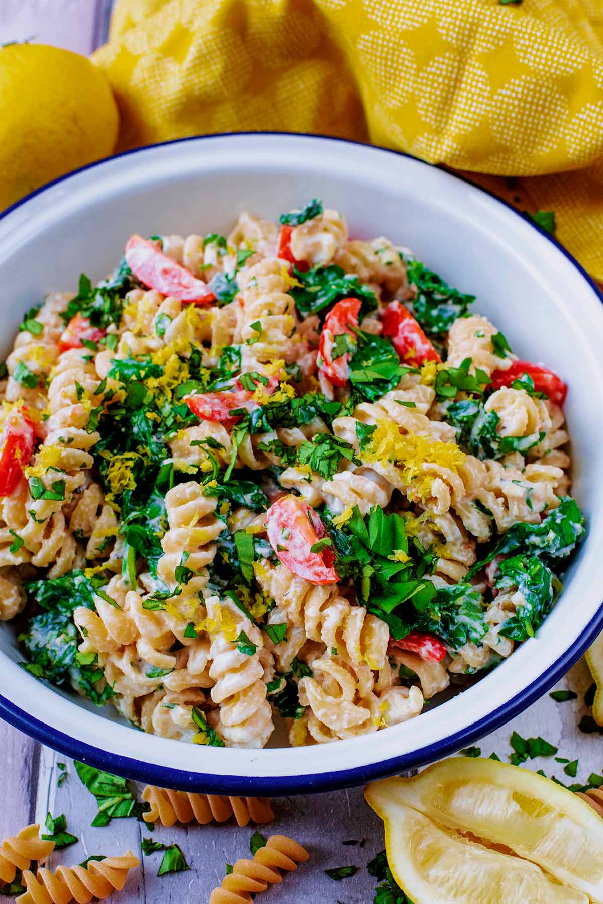 Fusilli pasta and spinach in a white bowl.