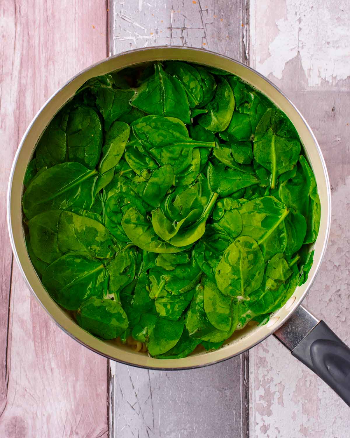 Spinach added to the pan of pasta.