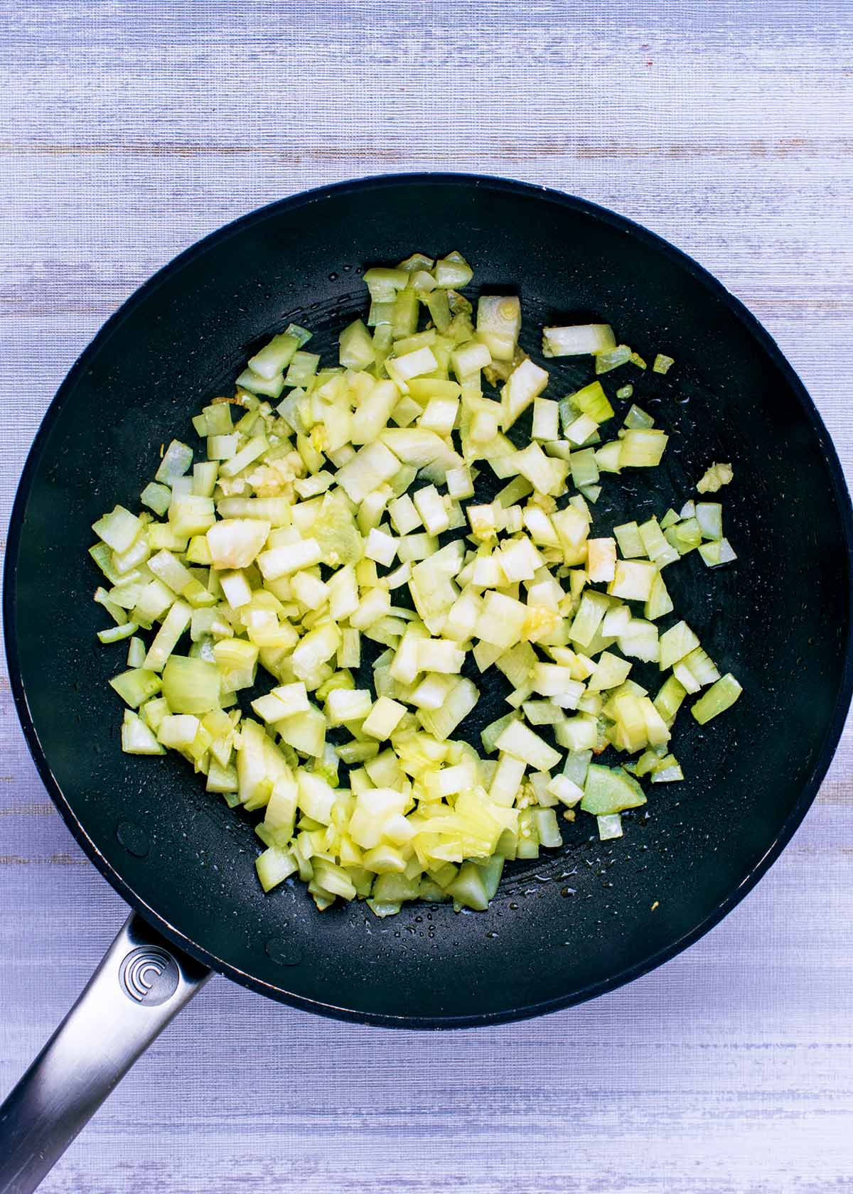A black frying ban with chopped onions in it.