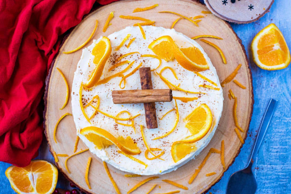 Cheesecake on a board topped with oranges and cinnamon.